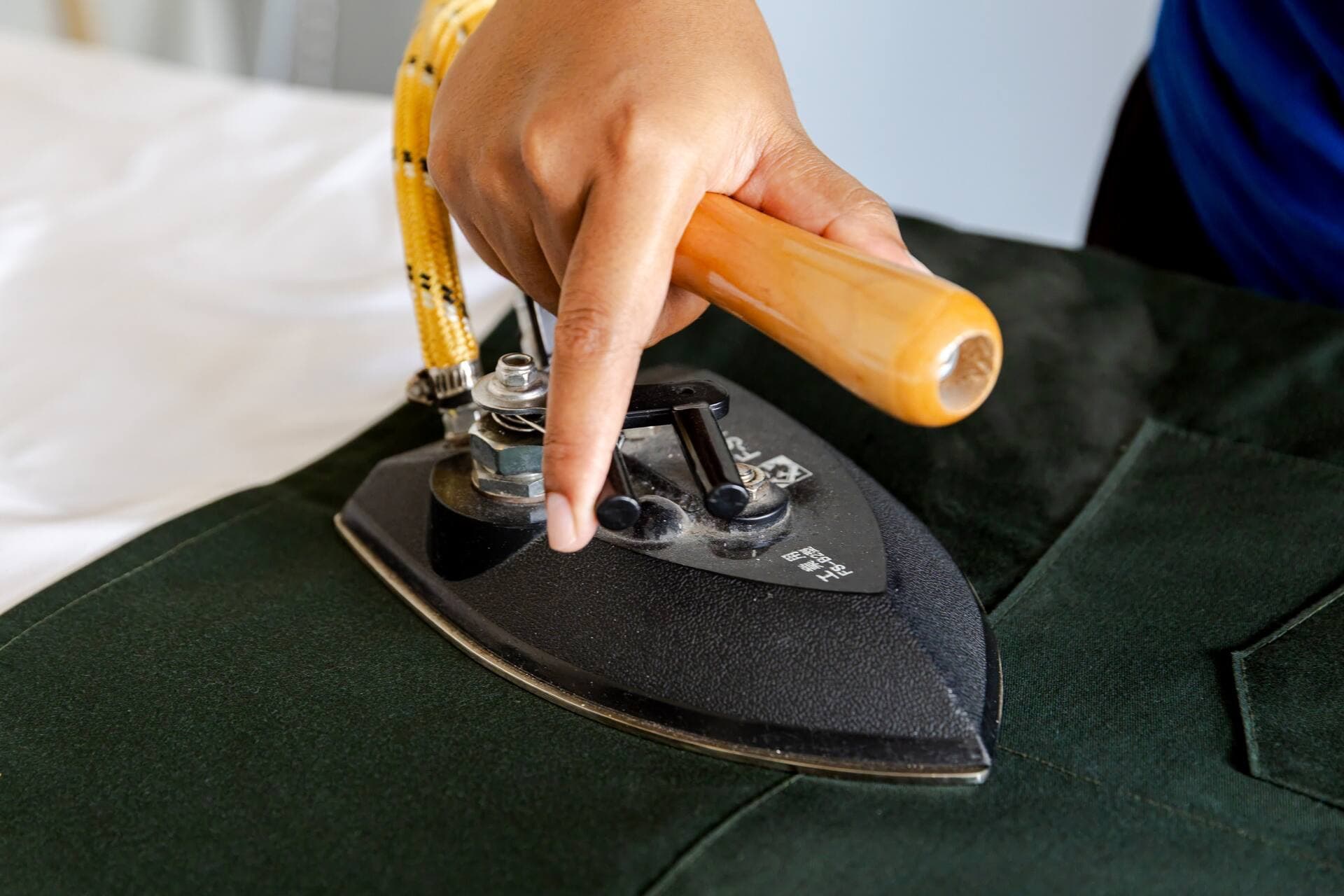 Close-up of an Easy Day Laundry team member pressing a garment with a professional steam iron