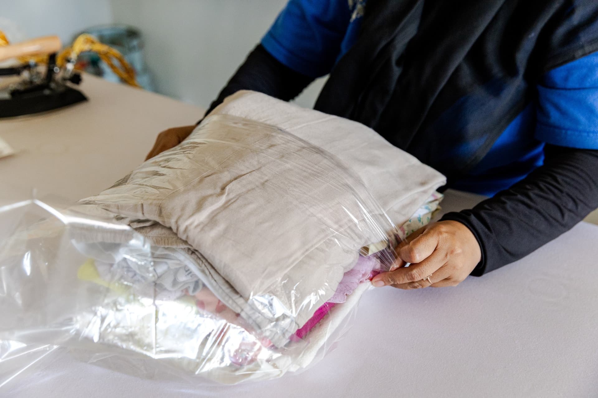 Easy Day Laundry team member packing freshly folded clothes into a bag for return