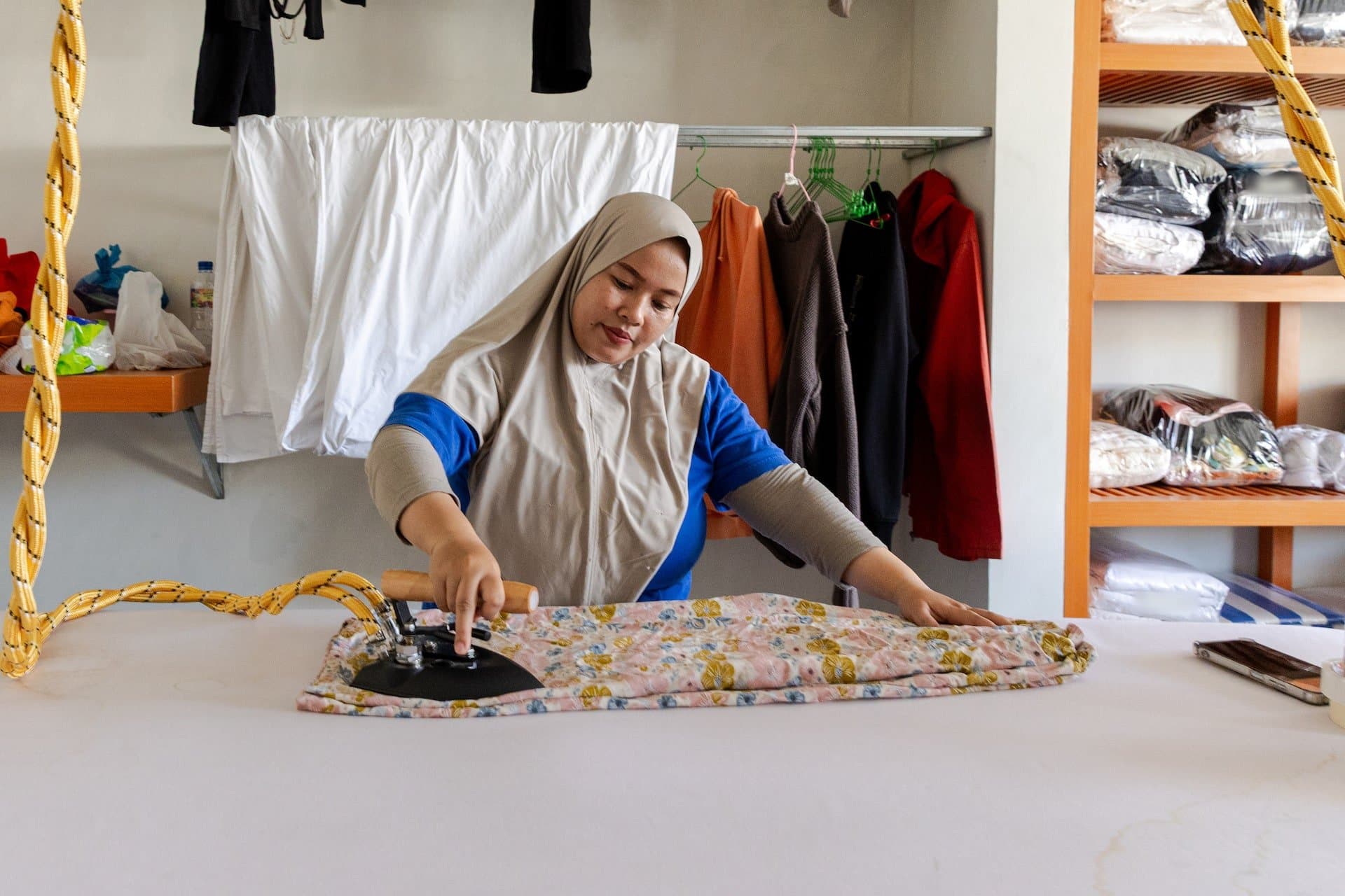 Easy Day Laundry team member hand-ironing a floral garment with a steam iron at a Bali shop