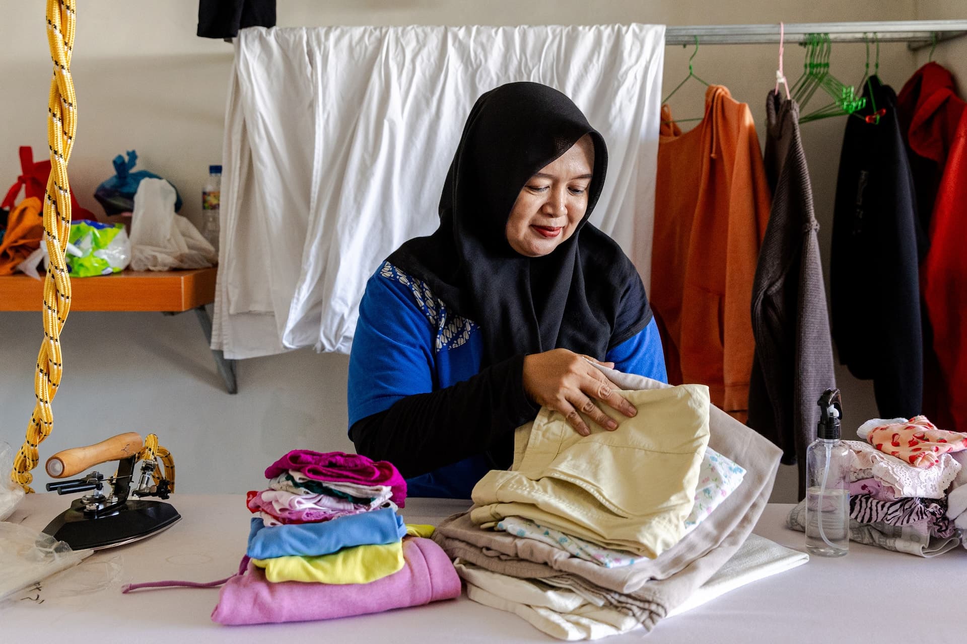 Easy Day Laundry team member folding clean clothes beside the ironing station